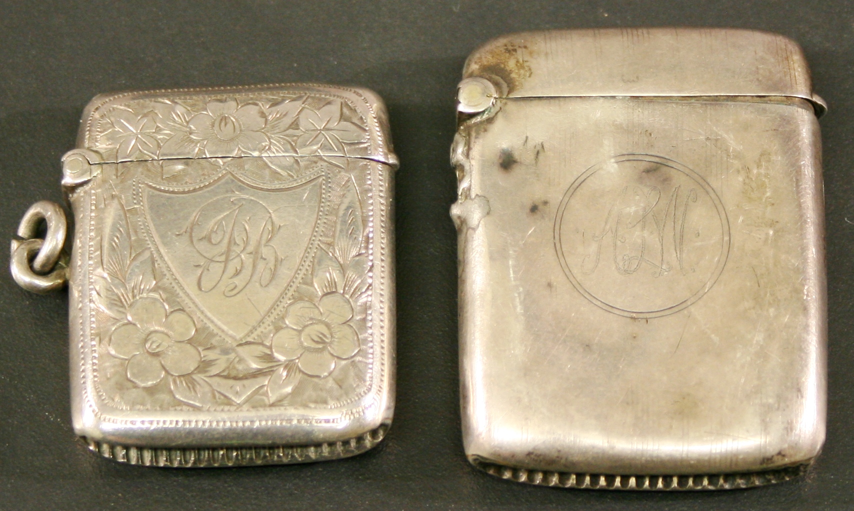 AN EDWARDIAN SILVER VESTA of hinged rectangular form with foliate engraving and shield cartouche