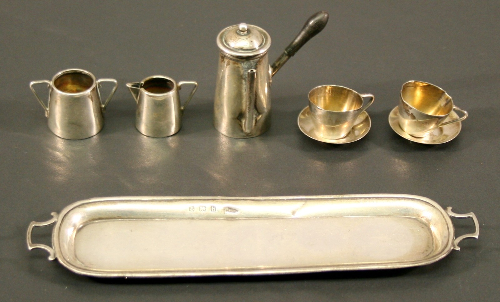 AN EDWARDIAN SILVER MINIATURE COFFEE SET comprising a coffee pot, sugar, cream two cups and