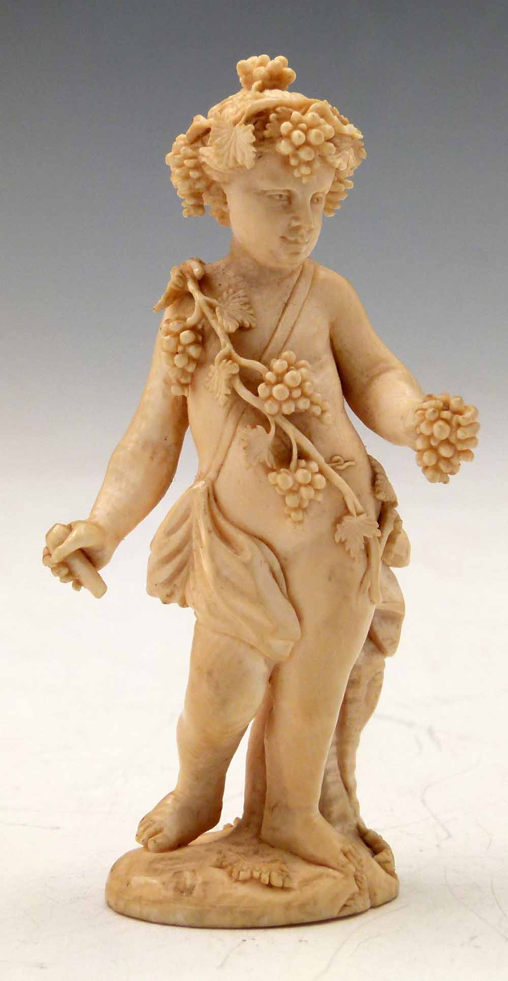 Carved ivory Bacchanalian standing figure of a boy draped with vines and grapes, leaning against a