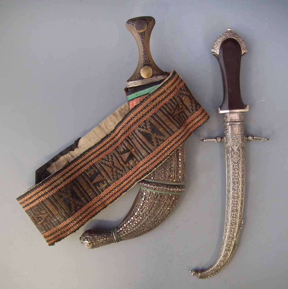 Two Arab white metal mounted Jambiyas,   one dated 1354 with wood grip, the second with belt and