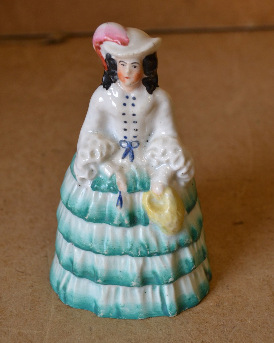 A Staffordshire China Candle Snuffer in form of a lady in sweeping dress, 12cm high