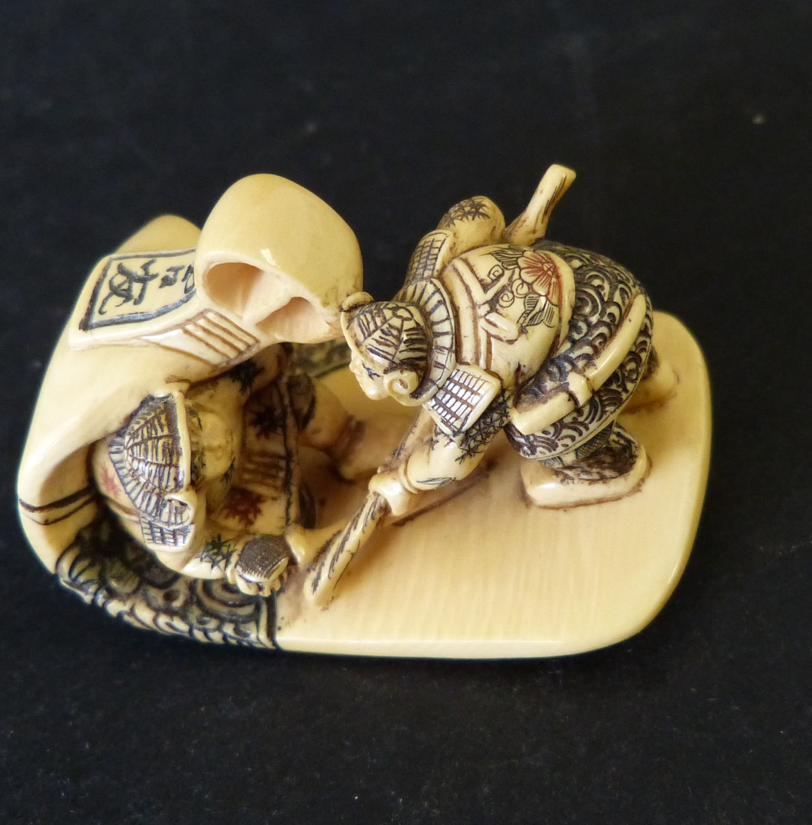 An Ivory Netsuke in form of a stirrup mounted with 2 miniature figures, 5cm long