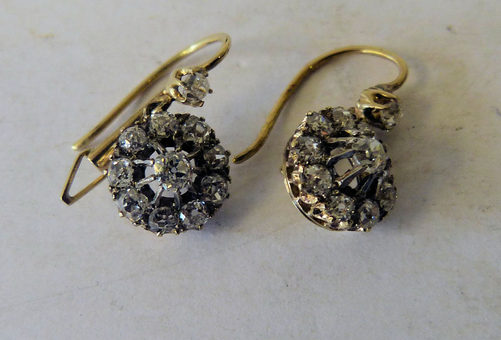 A Pair of Gold Drop Earrings mounted with centre diamonds each surrounded by 10 further diamonds