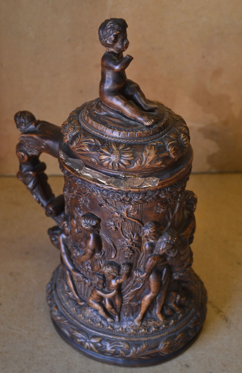 An Oval Lidded Tankard, on brown ground with raised figure, tree, floral and scroll decoration,