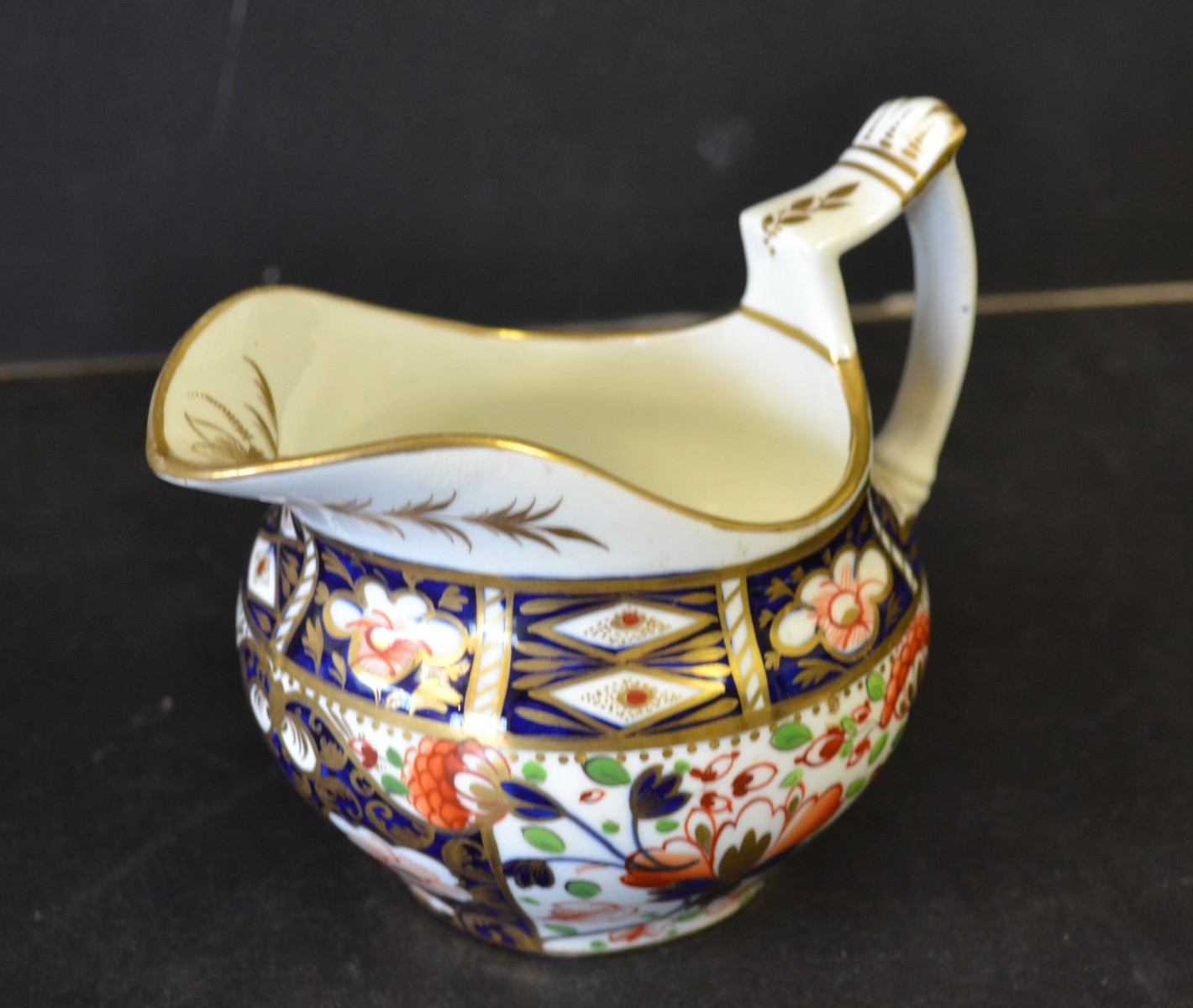 A Crown Derby Bulbous Shaped Milk Jug, on Imari pattern ground, having all over gilt decoration,