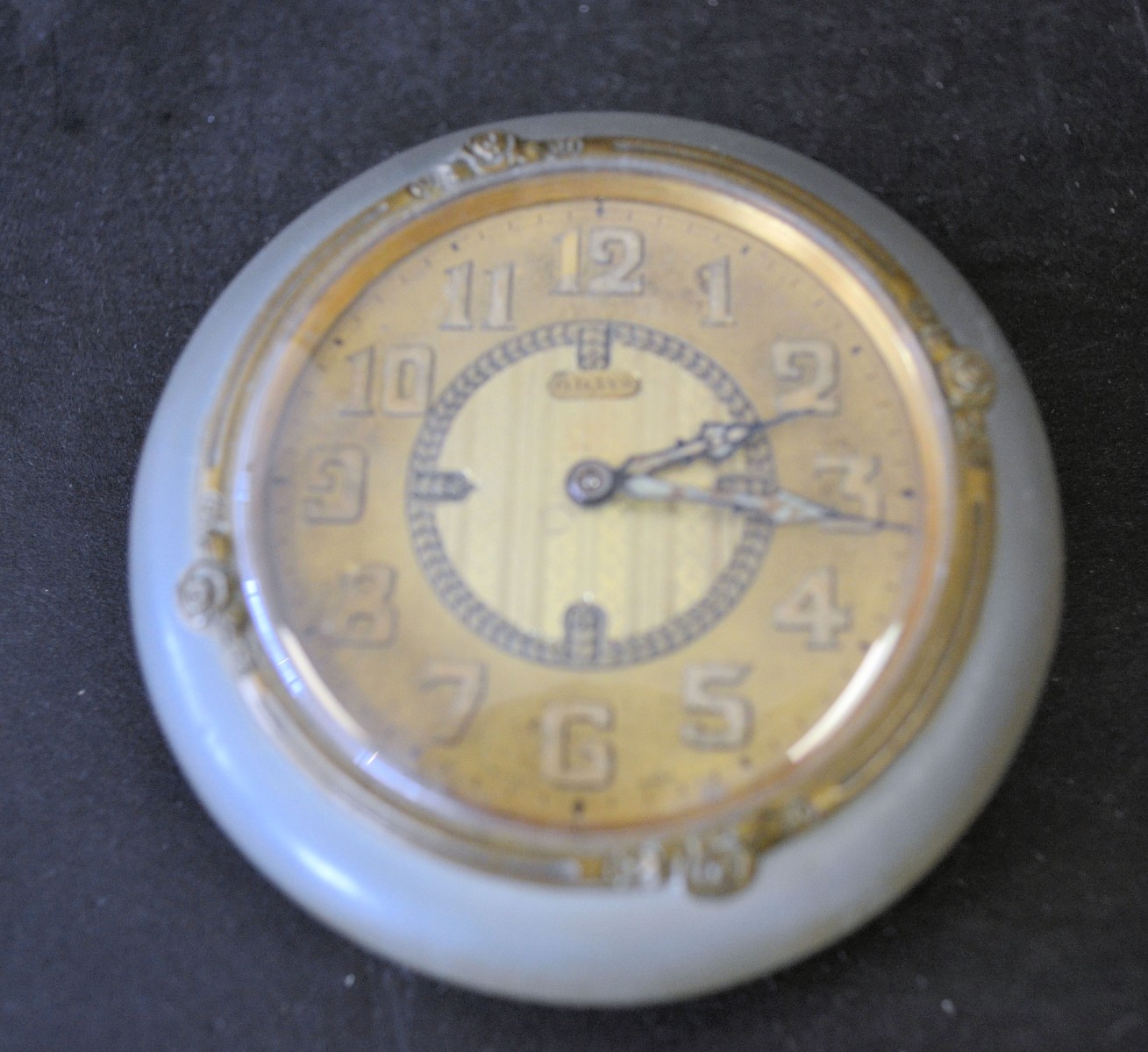 A Onyx and Gilt Metal Flat Circular Desk Top Timepiece having gilt dial with Arabic numerals on bun