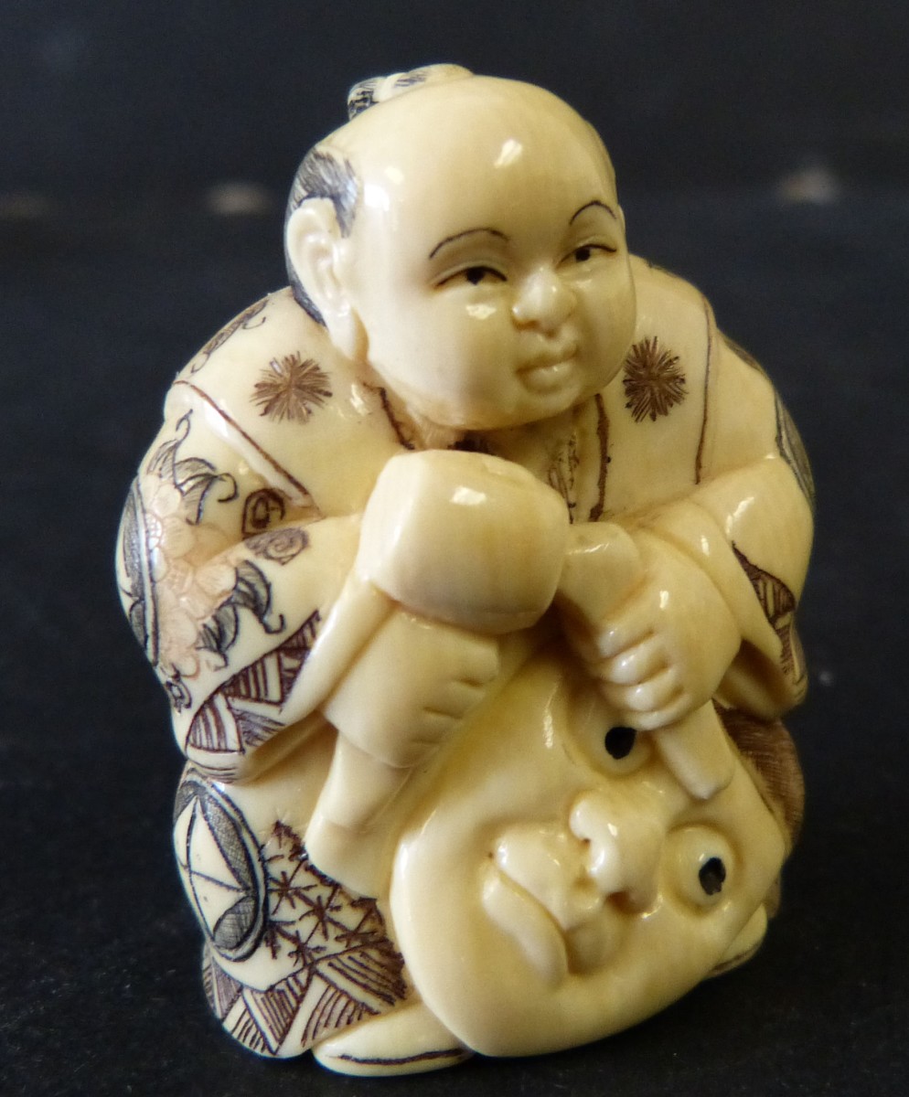 An Oriental Ivory Netsuke in form of a seated gentleman carving a mask, 4.5cm high