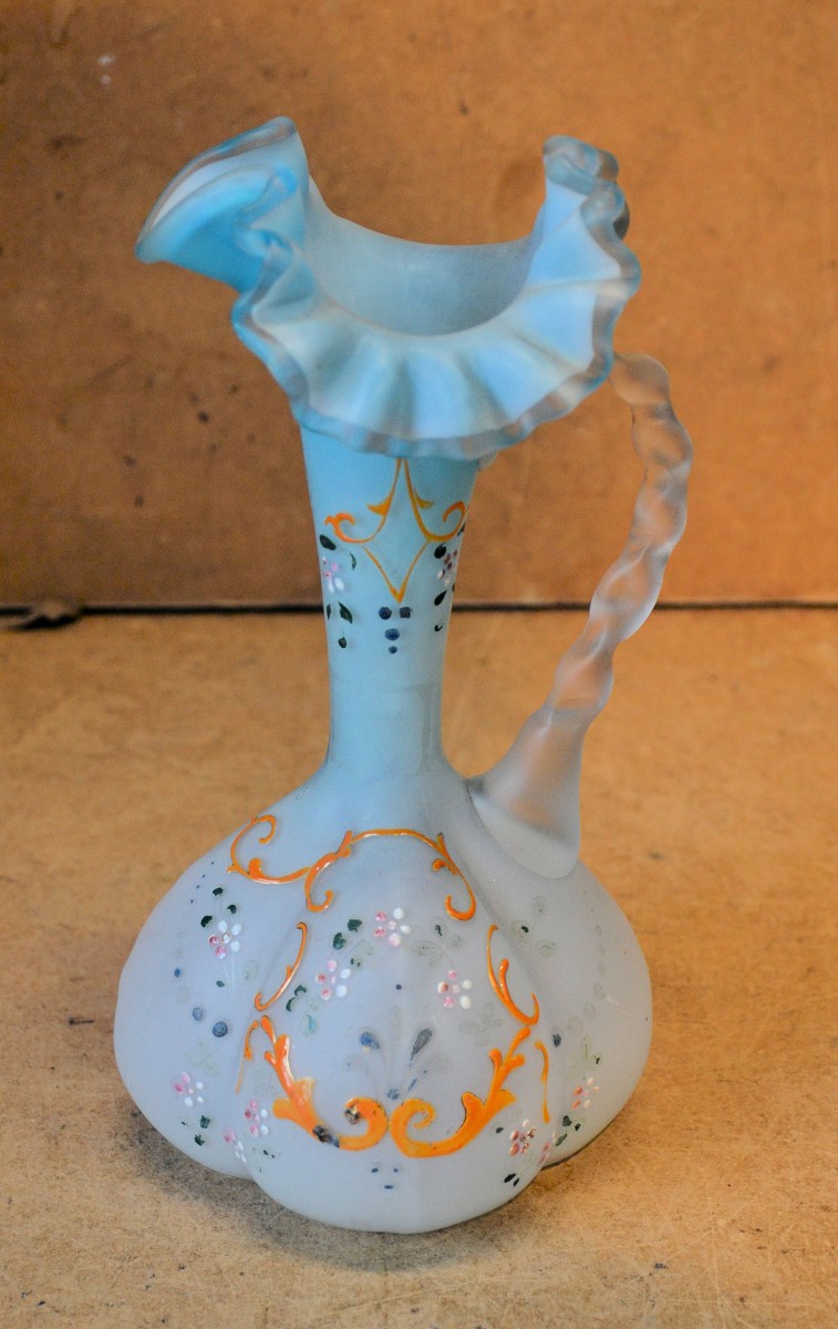 A Pale Blue Glass Bulbous Thin Necked Jug having crinkled rim, twist handle with raised floral,