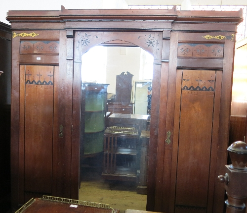 A late 19th century oak triple door wardrobe, in the Gothic style, the central mirror door opening