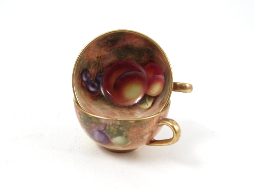 Two Royal Worcester miniature cabinet cups, the interiors and exteriors hand painted with fruit to a