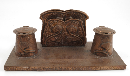 A beaten copper desk stand, in the Arts and Crafts style, the letter rack and pair of covered