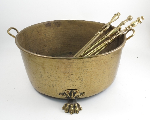 A large brass two handled pot, raised on three hairy paw feet, maximum diameter including handles