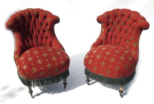 A pair of late 19th century ebonised salon chairs, with deep buttoned back, raised on short turned