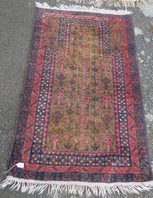 An Eastern prayer mat, with brown field decorated with repeating motifs, 4ft x 2ft6