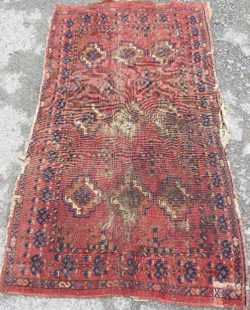 An Eastern rug, the red ground field and borders decorated with repeating motifs, 5ft x 2ft10