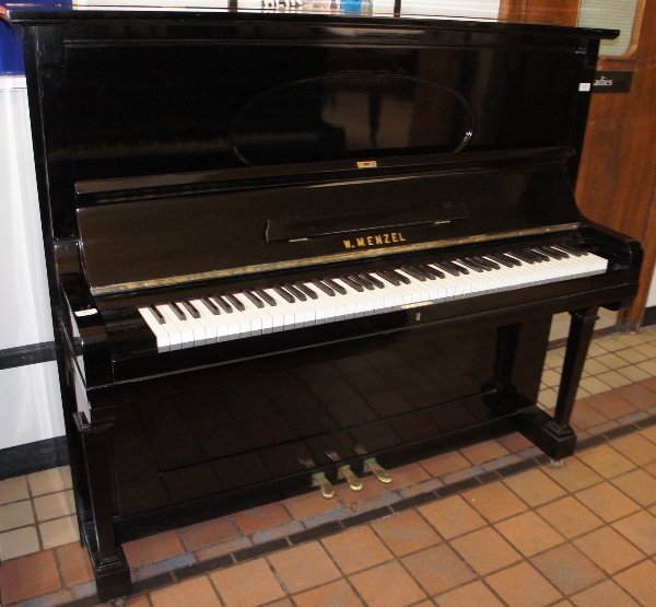 Menzel 
An upright piano in a bright ebonised case.  This piano has been completely restored and