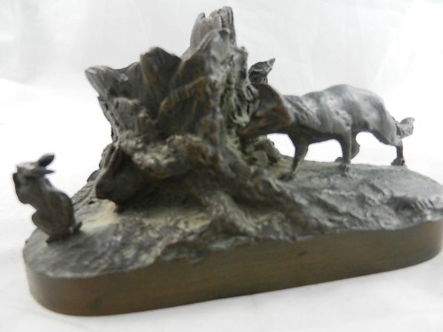 A late 19th/early 20th century bronze group of a fox behind a tree stump watching two rabbits,