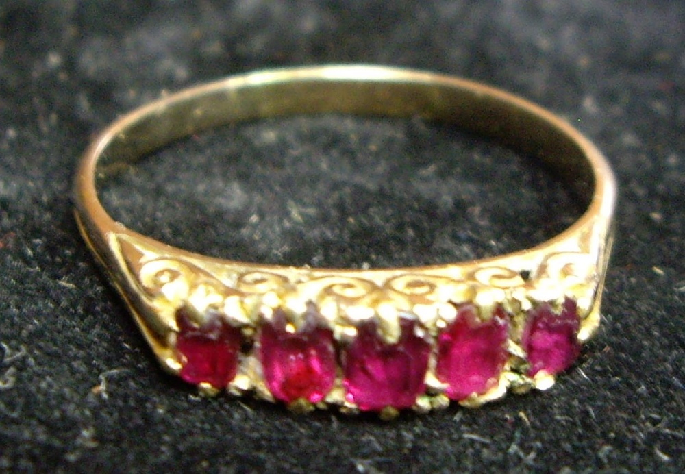 An early 20th century carved half hoop yellow metal five stone ruby ring, 2.1g