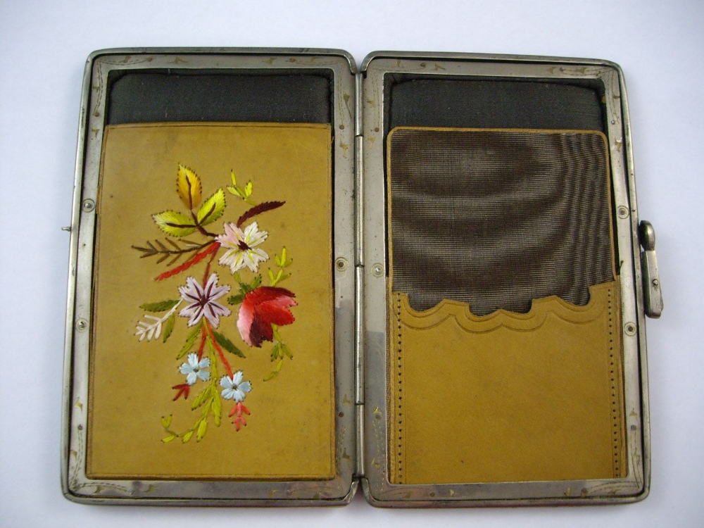 An early 20th century pig skin wallet, the interior with embroidered design and containing a
