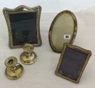 Three silver photo frames and a pair of short silver candlesticks