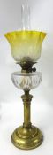 A tall brass and glass oil lamp with yellow and etched shade