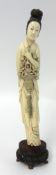 A Chinese carved ivory figure of a women with flowers and flute behind her back on carved wood