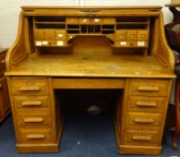 A large oak roll top desk, with tambour front over an arrangement of drawers, the interior fitted