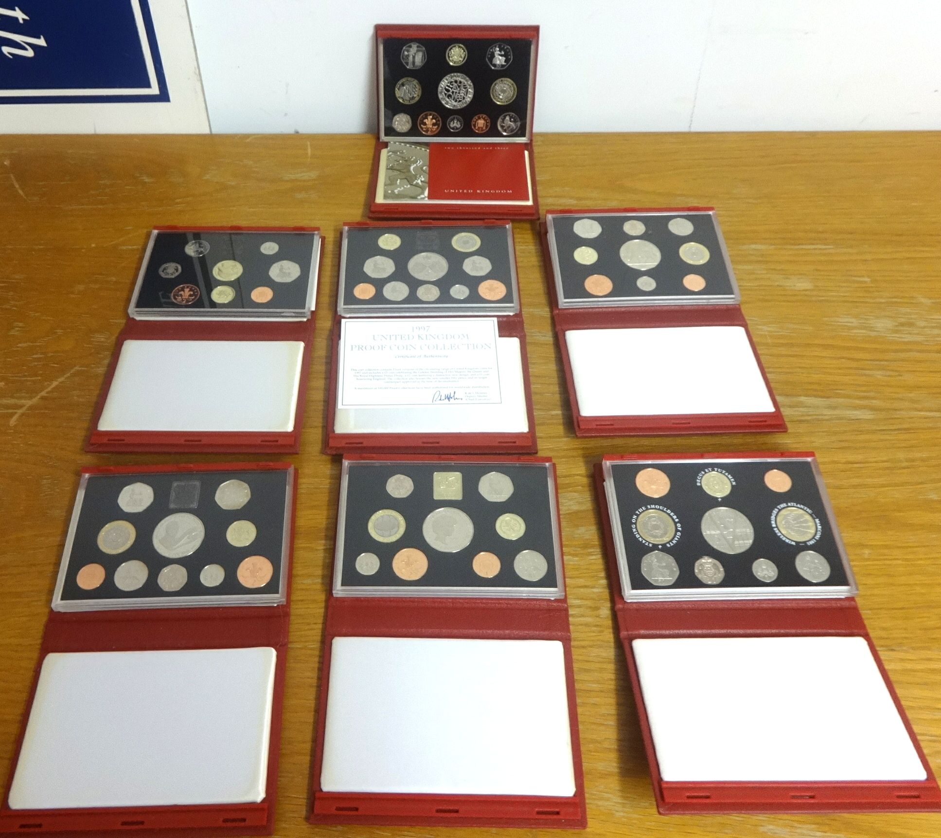 Eight Royal Mint UK proof year sets in red wallets