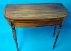 A George III mahogany fold over tea table on turned legs