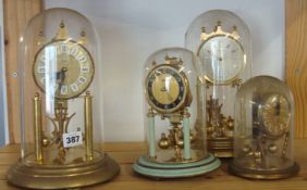 Four German 300 day anniversary clocks under domes also glass domes