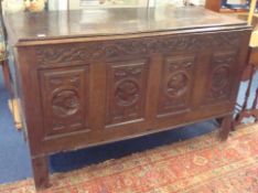 A large antique carved oak chest decorated with four portrait panels, raised on straight legs,