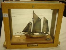Modern silver model of a traditional ketch mounted on a wood base with later cabinet
