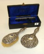 Three piece silver back dressing table set with ornate embossed decoration in fitted box