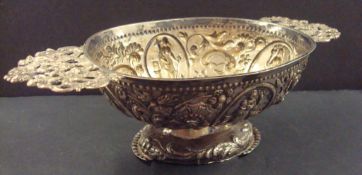 Foreign solid silver oval sweet dish with cherub, pierced handles and embossed scroll decoration.