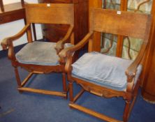 Pair carved oak elbow chairs, the arms decorated with carved rams heads, with loose cushions