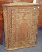 19th century carved oak hanging corner cupboard decorated with a heraldic crest, another corner
