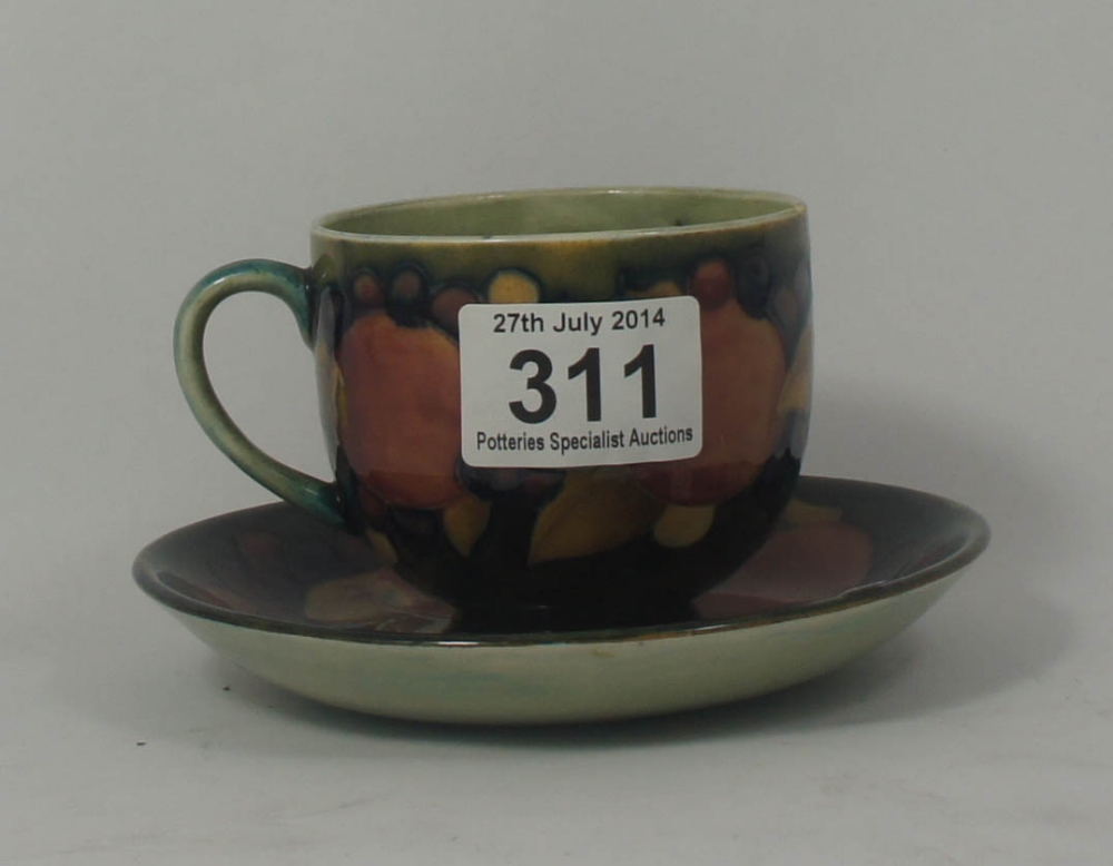 A Moorcroft cup and saucer pomegranate design (chip to rim)