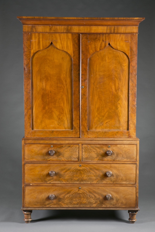 A linen press with book matched mahogany veneer. 19th c.  Incorporating a ogee arch on top panel