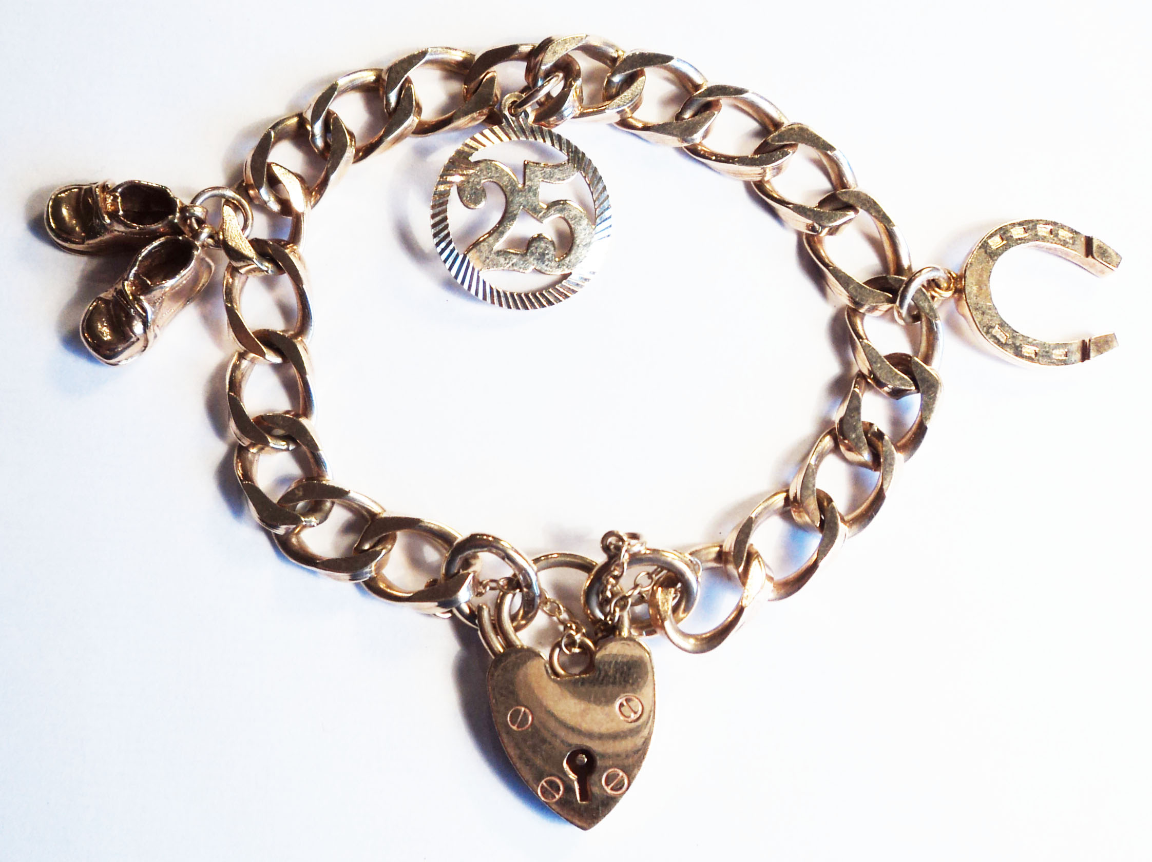 A 9ct. gold kerb-link charm bracelet, with heart shaped padlock and safety chain