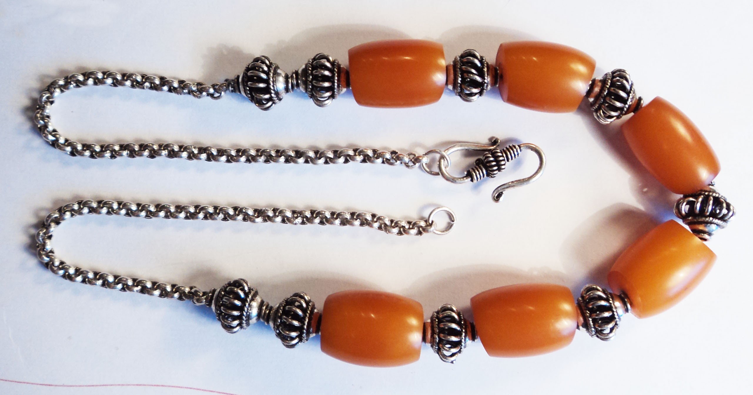 A vintage amber bead and white metal necklace with elephant bell pattern links