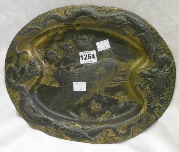 An Oriental gilt bronze dish with central peacocks and chrysanthemum decoration within a dragon