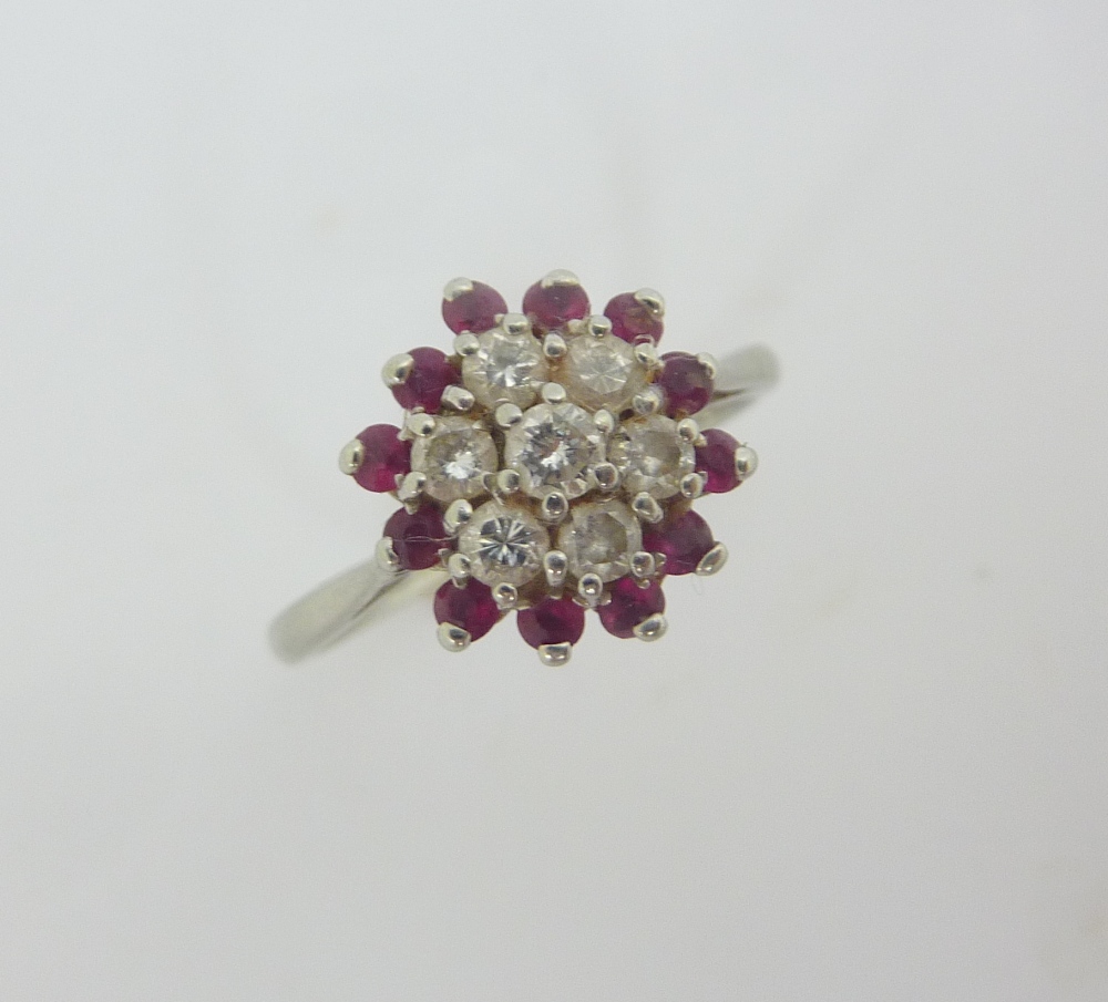 AN 18CT WHITE GOLD DIAMOND AND RUBY CLUSTER RING, the seven brilliant cut diamonds within a surround