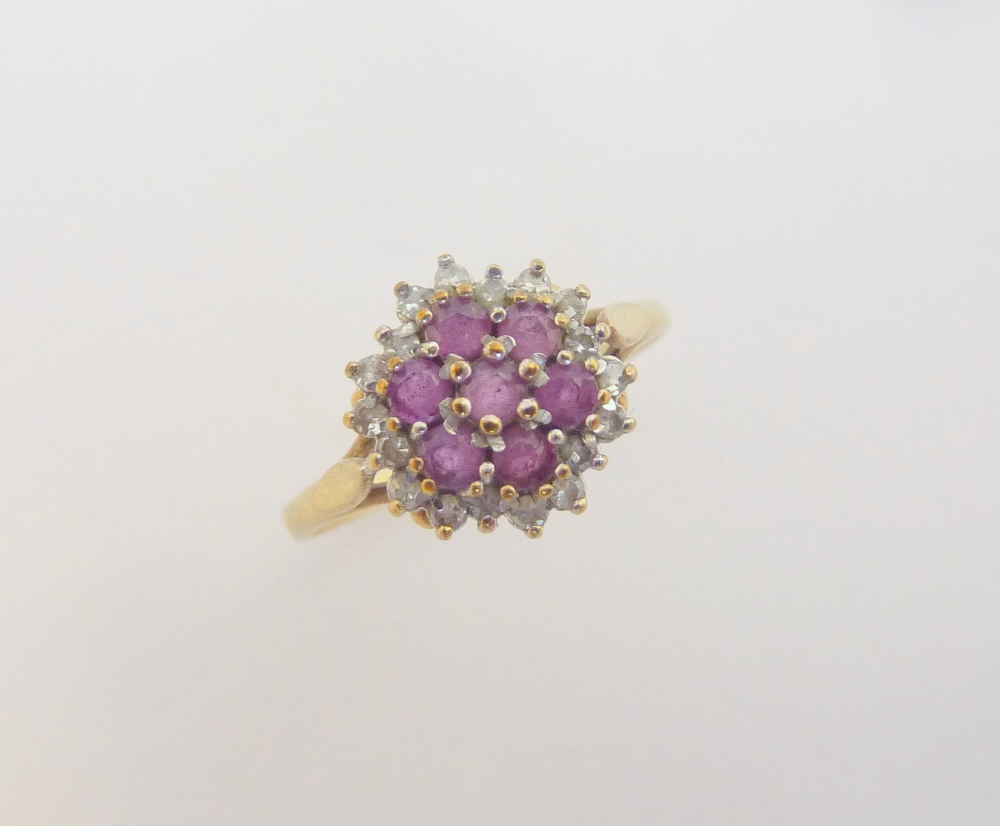 A 9CT GOLD RUBY AND DIAMOND RING, the seven rubies in a flower shape with a surround of single cut