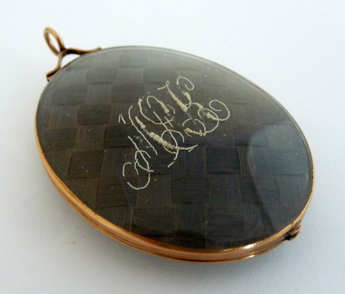 A LARGE OVAL MOURNING LOCKET, 19th century, with inter-woven brunette hair to each side of the