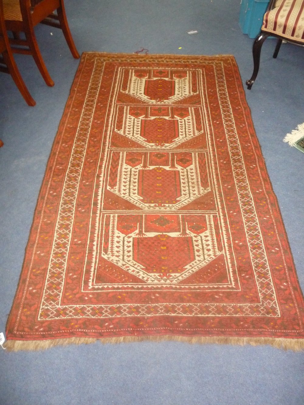 A RED GROUND RUG, approximate size 200cm x 110cm