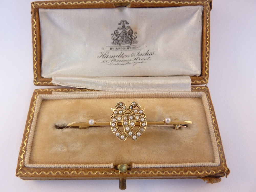 A PEARL BAR BROOCH, of two entwinned hearts with bow detail to the top with seed pearl detail to
