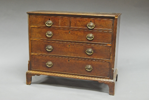 A George III mahogany chest, of two short and three long graduated drawers, flanked by crossbanded