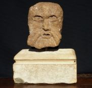 A carved stone head
Formed as as a green man, mounted on a carved stone plinth base.  34 cms high