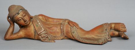 An Indian carved wooden model of a recumbent Buddha
With iron red and gilt decoration, typically