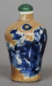 A Chinese porcelain snuff bottle
The mottled ground decorated in blue and white with scholarly